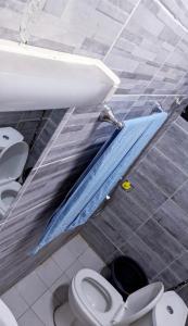 baño con 2 aseos, lavamanos y sábana azul en RAMS ENG ROME appartement meublé en Douala