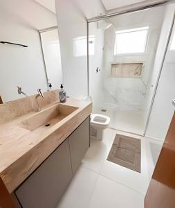 uma casa de banho branca com um lavatório e um WC em M203- Apartamento c/ Suíte Completo Patos de Minas em Patos de Minas