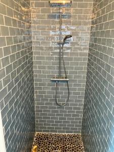 La salle de bains est pourvue d'une douche avec un tuyau et de carrelage bleu. dans l'établissement Welcoming new architects house with jacuzzi, à Hourtin