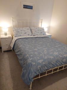 een slaapkamer met een bed met een blauw dekbed en 2 lampen bij 2 bed barn with spectacular views - Wye Valley in Symonds Yat