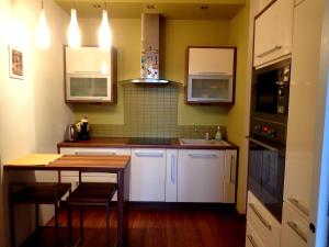 a kitchen with white cabinets and a wooden table at Apartment in the heart of Bratislava in Bratislava