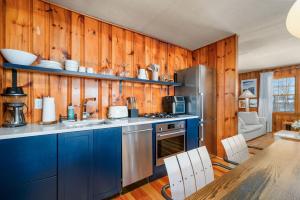 een keuken met blauwe kasten, een koelkast en een tafel bij 4 Manning Road Dennis Port Cape Cod - Blue Sky in Dennis Port
