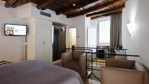 a bedroom with a bed and chairs and a television at Santa Chiara Boutique Hotel in Naples