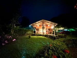 un invernadero iluminado por la noche con un patio en Romantic Private Cabin in the Forest, Bungalows Tulipanes, en San Ramón