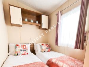 2 camas en una habitación pequeña con ventana en Homely 3 bed - Sleeps 8 @ Seal Bay, Selsey en Chichester