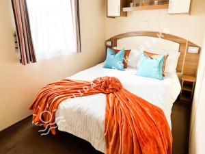 Un dormitorio con una cama con una manta naranja. en Homely 3 bed - Sleeps 8 @ Seal Bay, Selsey en Chichester