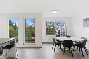 ein weißes Zimmer mit einem Tisch, Stühlen und Fenstern in der Unterkunft Tranquil Haven - Relax and Unwind in Hamm ID23 in Luxemburg (Stadt)