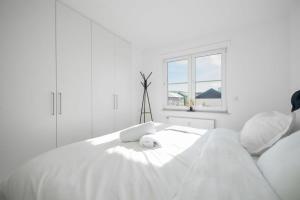 Cama blanca en habitación blanca con ventana en Modern Penthouse in Sanem, en Sanem