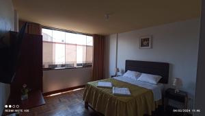 um quarto com uma cama e uma grande janela em Montecristo Hotel em Tacna