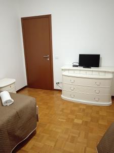a bedroom with a bed and a dresser with a laptop on it at Elisa's House, Una coccola! in Castel San Pietro Terme