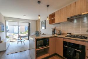 a kitchen with wooden cabinets and a large window at Amazing 1BR with modern balcony in San Isidro in Lima