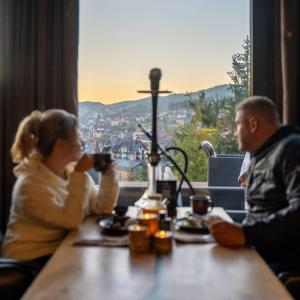 Ein Mann und eine Frau sitzen am Tisch und trinken Kaffee. in der Unterkunft Phoenix Relax Park in Bukowel