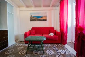 un soggiorno con divano rosso e sgabello di AFFITTACAMERE ANEMONE- SCIROCCO1 a Uggiano la Chiesa