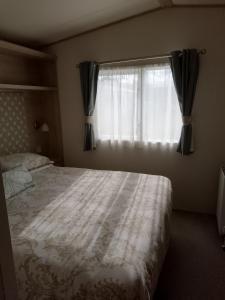 1 dormitorio con cama y ventana en Seasalter Cosy Caravan, en Seasalter