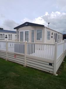 a large white house with a white fence at Seasalter Cosy Caravan, in Seasalter