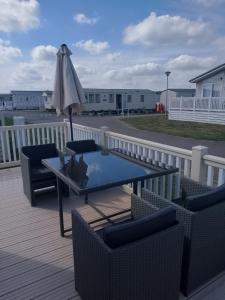 a patio with a table and chairs and an umbrella at Seasalter Cosy Caravan, in Seasalter