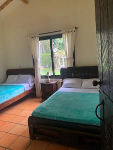 1 dormitorio con 2 camas y ventana en Casa Panaca Portal 12, en Quimbaya