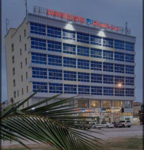un grand bâtiment avec un panneau en haut dans l'établissement Qasayed Hotel Salalah, فندق قصائد صلالة, à Salalah