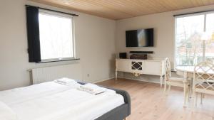 een slaapkamer met 2 bedden, een bureau en een televisie bij Hotel Smedegaarden in Lem