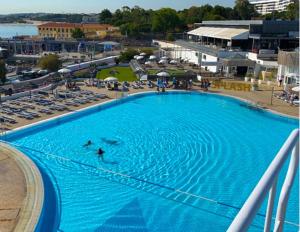 a large blue swimming pool with people swimming in it at Durma a bordo de um veleiro moderno em Oeiras in Oeiras