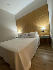 a bedroom with a white bed with a wooden wall at La Posada de San Miguel in Andújar