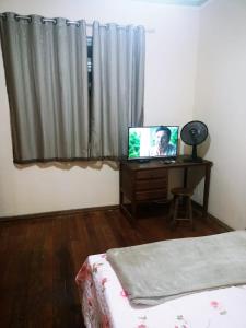 Pouso da Praça في Bonfim: غرفة نوم مع تلفزيون على طاولة أمام النافذة