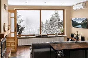 ein Wohnzimmer mit einem Sofa und einem großen Fenster in der Unterkunft Apartament widokowy z jacuzzi i sauną na wyłączność - Sikorówka - Dobre Miejsce in Wisła