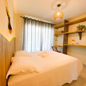 Schlafzimmer mit einem großen weißen Bett und einem Fenster in der Unterkunft Residencial Mãe terra in Bombinhas