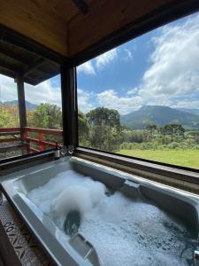 a bath tub filled with snow in front of a window at Chalés incríveis com banheira de hidromassagem e vista encantadora in Urubici