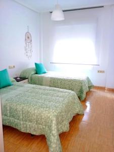 Cette chambre comprend 2 lits avec des draps verts et une fenêtre. dans l'établissement Confortable y nuevo cerca del Casco antiguo, à Caravaca de la Cruz