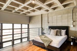 um quarto com uma cama com lençóis brancos e almofadas em Downtown Loft by ULIV em Tijuana