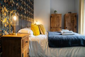 1 dormitorio con 1 cama con manta azul y almohadas amarillas en Sun Street Cottage - with log burner, jet bath and Summerhouse en Haworth