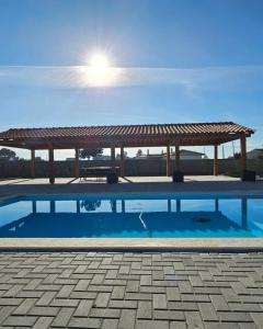 a pavilion with a picnic table and a swimming pool at Quinta Marinhais para férias no Ribatejo in Marinhais