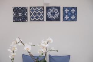 quattro piatti bianchi e blu su un muro con fiori di San Liborio Suites a Napoli