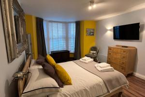 a bedroom with a bed with yellow walls and a television at Seaside Hideaway - Free Onstreet Parking in Scarborough