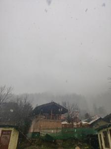 una vista desde una ventana de una casa en la nieve en Kasol Village Camp, en Kasol
