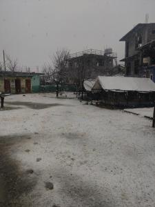 a parking lot with snow on the ground and buildings at Kasol Village Camp in Kasol