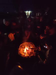 a group of people sitting around a fire in the dark at Kasol Village Camp in Kasol