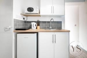 una cocina con armarios blancos y fregadero en Spacious 5 En-Suite BR Apartment - Corporate Stay, en Stoke on Trent