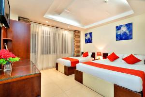 a hotel room with two beds and a desk at HANZ The Beautiful Hotel Bui Vien Walking Street in Ho Chi Minh City