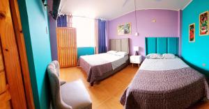 Duas camas num quarto com paredes roxas e azuis em La Casa de Bamboo em Ica