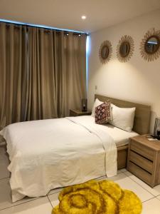 a bedroom with a large white bed and two mirrors at Embasy Gardens by Rosy Apartments in Accra
