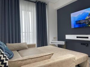 um quarto com uma cama e uma televisão na parede em Акай сити Белая студия em Tashkent