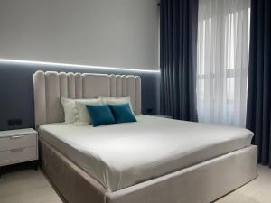 um quarto com uma cama grande e almofadas azuis em Акай сити Белая студия em Tashkent
