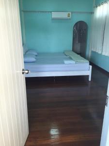 a small bed in a room with a wooden floor at Baan Songsri in Amphawa
