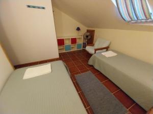 een kleine kamer met 2 bedden en een stoel bij Supertubos Beach Hostel in Peniche