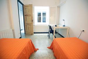 two orange beds in a room with a desk and a window at Apartamento céntrico en Sant Feliu de Guíxols in Sant Feliu de Guíxols