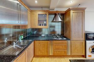 a kitchen with wooden cabinets and a sink at City Centre Sleeps up to 6 in Nottingham