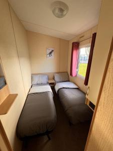 Duas camas num pequeno quarto com uma janela em 3 bedroom pet friendly Lyons Winkups Towyn em Abergele