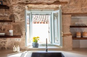 een keuken met een wastafel en een raam bij Wood and Stone Ηouse in Aegina Town